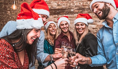 Merry Christmas And Happy New Year! Multiracial Young Smiling Friends Are Celebrating Holiday In Bar Group Of Young Business People Are Toasting And Drinking Champagne In Coworking