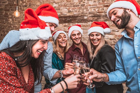 Merry Christmas And Happy New Year! Multiracial Young Smiling Friends Are Celebrating Holiday In Bar Group Of Young Business People Are Toasting And Drinking Champagne In Coworking